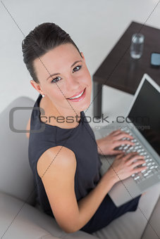 Beautiful well dressed young woman using laptop on sofa