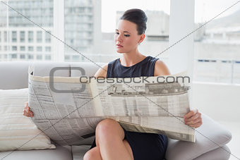 Beautiful businesswoman reading newspaper on sofa
