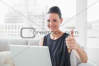 Beautiful well dressed woman with laptop gesturing thumbs up