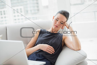 Beautiful well dressed woman resting on sofa while using laptop