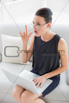 Thoughtful and expressive well dressed woman using laptop