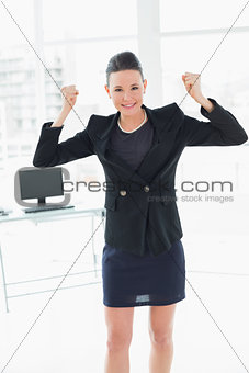 Elegant and happy businesswoman clenching fists in office