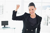 Elegant and happy businesswoman clenching fist in office