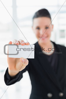 Blurred businesswoman holding up a business card