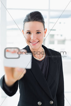 Elegant businesswoman holding up a business card in office