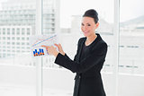 Smiling businesswoman pointing at graphs in office