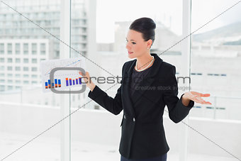Businesswoman with graphs standing in bright office