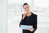 Thoughtful elegant businesswoman holding tablet PC