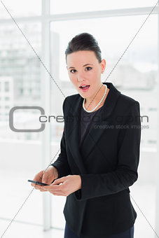 Portrait of a shocked elegant young businesswoman with a mobile phone