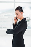 Elegant businesswoman using cellphone while checking time