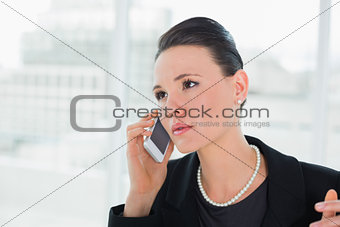 Serious elegant businesswoman using cellphone