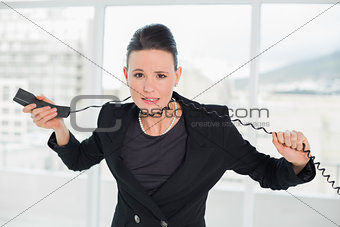Frustrated elegant businesswoman with telephone cable around her neck