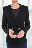 Mid section of businesswoman in suit holding a cellphone