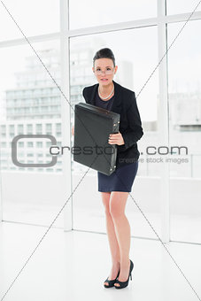 Elegant businesswoman in suit carrying briefcase in office