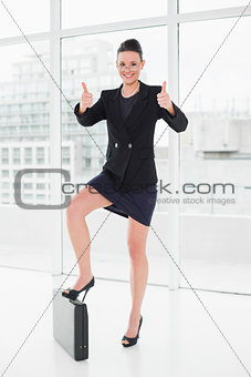 Elegant businesswoman with briefcase gesturing thumbs up