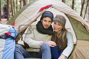 Smiling couple in tent with backpack in the wilderness