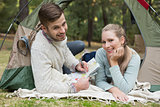 Smiling couple  with a map lying in tent