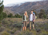 Couple with backpacks and trekking poles against mountain