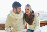 Couple in winter clothing sitting against window