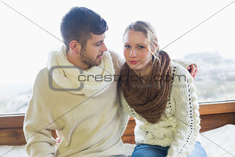 Couple in winter clothing sitting against window