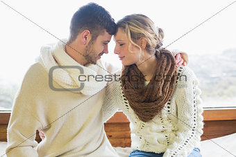 Loving couple in winter clothing against window