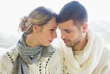 Loving couple in winter clothing against bright background