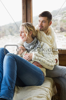 Couple in winter wear looking out through cabin window