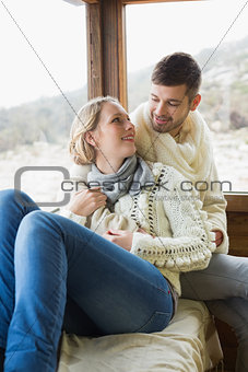 Loving couple in winter clothing sitting in cabin