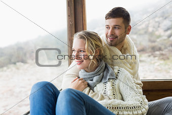 Couple in winter wear looking out through cabin window