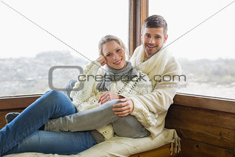 Couple in winter clothing sitting against cabin window