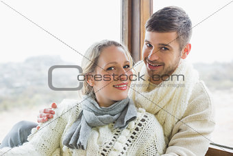 Couple in winter clothing against cabin window