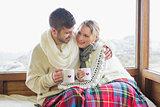 Loving couple in winter wear with cups against window