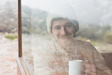 Smiling man with coffee cup looking through window