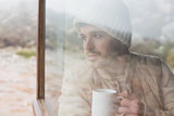 Thoughtful man with cup looking out through window