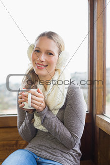 Woman wearing earmuff with cup against window