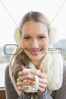 Smiling woman wearing earmuff with drinking coffee