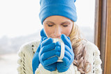 Cute woman drinking coffee in warm clothing