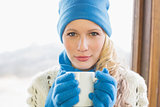 Cute woman with coffee cup in warm clothing