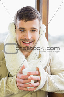 Smiling man wearing earmuff with coffee cup