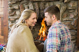 Loving couple looking at each other in front of lit fireplace