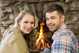 Smiling young couple in front of lit fireplace