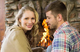 Smiling young couple in front of lit fireplace