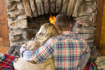 Romantic couple sitting in front of lit fireplace