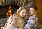 Romantic young couple in front of lit fireplace
