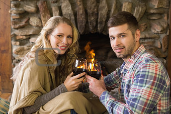 Romantic couple toasting wineglasses in front of lit fireplace