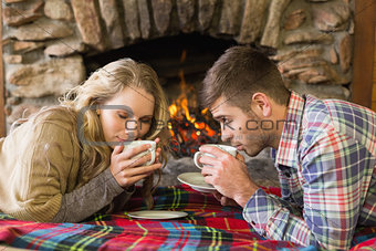 Romantic couple drinking tea in front of lit fireplace