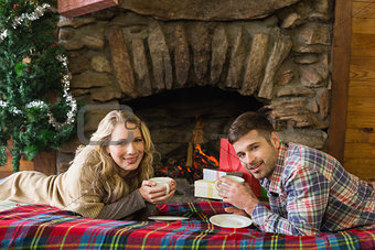 Couple with tea cups in front of lit fireplace