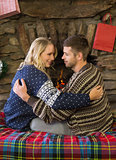 Loving couple looking at each other in front of lit fireplace