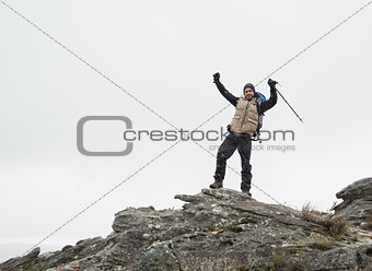 Man with hands raised on rock against the sky