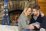 Romantic couple with arms around in front of lit fireplace